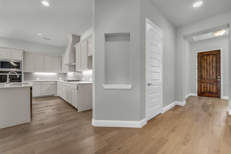 Kitchen with recessed lighting, light wood-style floors, tasteful backsplash, white cabinets, and stainless steel appliances