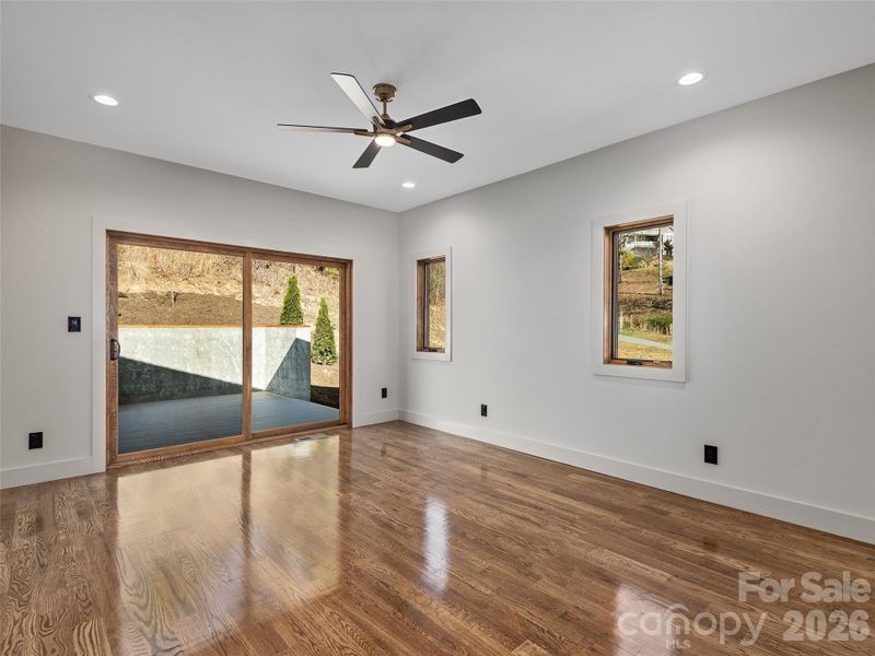 Primary bedroom with oak hardwood floors, ensuite bath, and large sliding doors opening to the spacious rear deck.