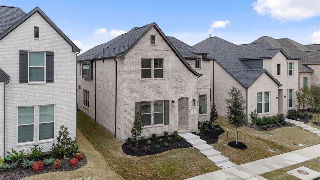 French country home featuring brick siding and a front lawn