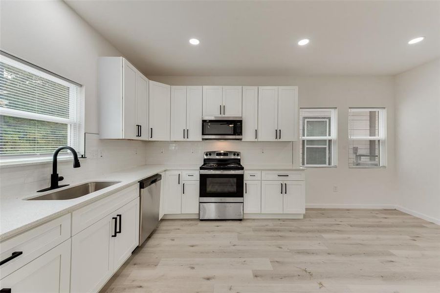 Kitchen featuring light hardwood / wood-style flooring, stainless steel appliances, white cabinetry, and sink