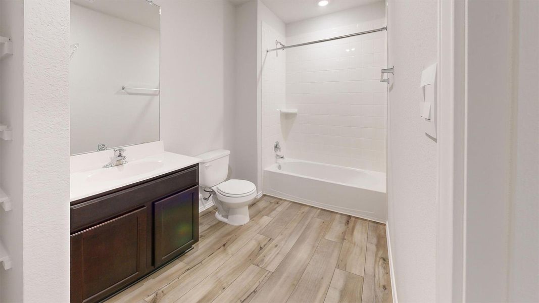 Bathroom with light wood finished floors, vanity, tub / shower combination, and recessed lighting