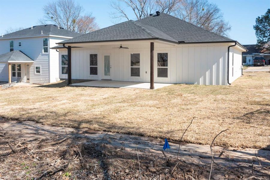 Rear view of house with ceiling fan, a patio area, and a lawn