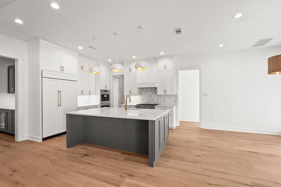 Kitchen featuring gray cabinetry, white cabinets, pendant lighting, a center island with sink, and light wood-style flooring Kitchen featuring gray cabinetry, white cabinets, pendant lighting, a center island with sink, and light wood-style flooring
