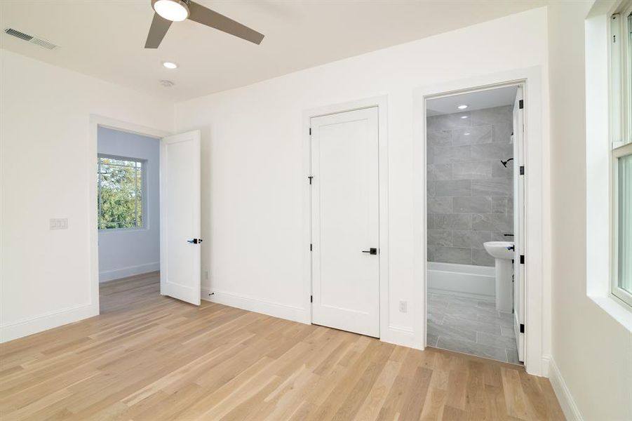 Unfurnished bedroom with ceiling fan, ensuite bath, and light wood-type flooring