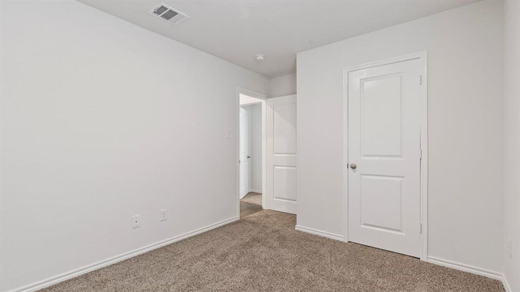 Unfurnished bedroom with dark colored carpet and baseboards