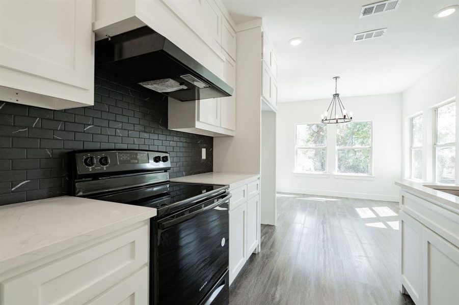 Kitchen featuring black electric range, hardwood / wood-style flooring, an inviting chandelier, and white cabinetry