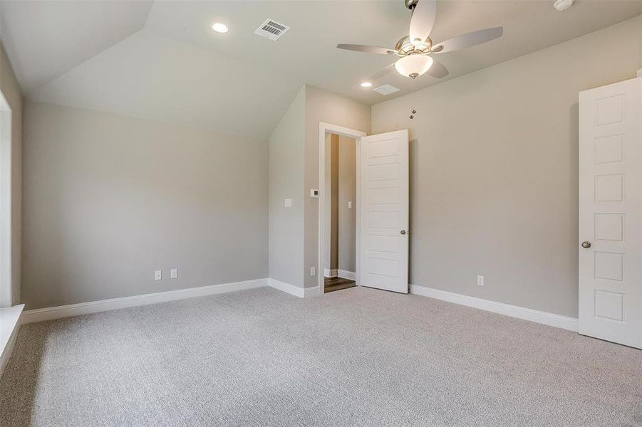 Empty room with lofted ceiling, carpet floors, and ceiling fan