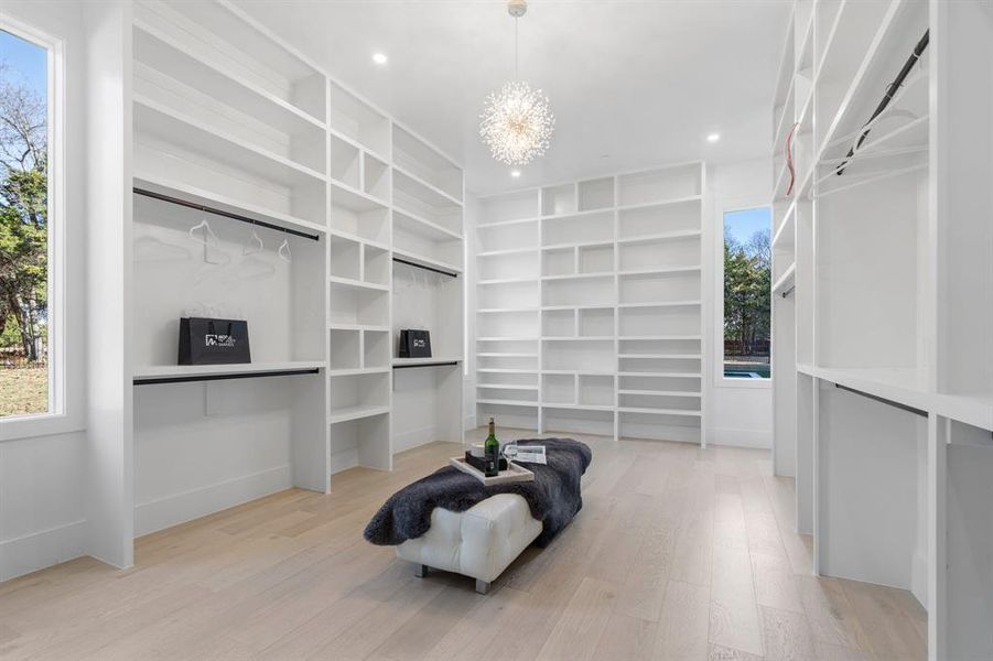 Spacious closet with a notable chandelier and light hardwood / wood-style floors