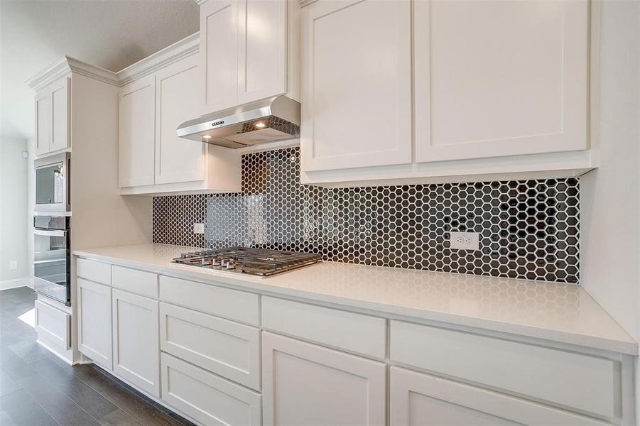 Kitchen featuring backsplash, white cabinetry, exhaust hood, appliances with stainless steel finishes, and dark hardwood / wood-style floors