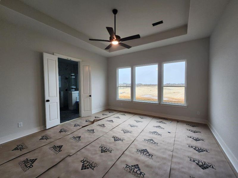 Empty room featuring a raised ceiling and a ceiling fan