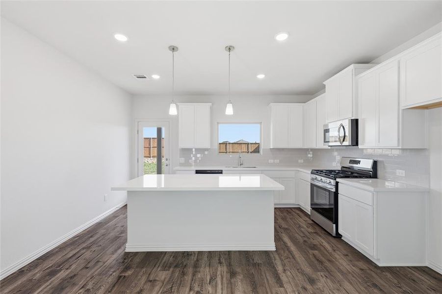 Contemporary kitchen featuring an island, white cabinetry, stainless steel appliances, wood-finish flooring, and recessed lighting