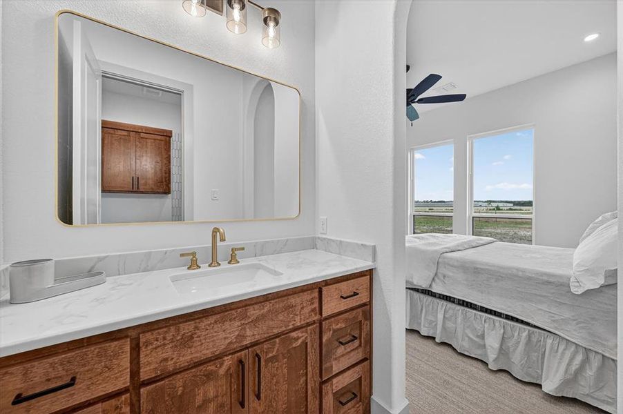 White vanity with a rectangular undermount sink, brass-finish faucet, and a large framed mirror