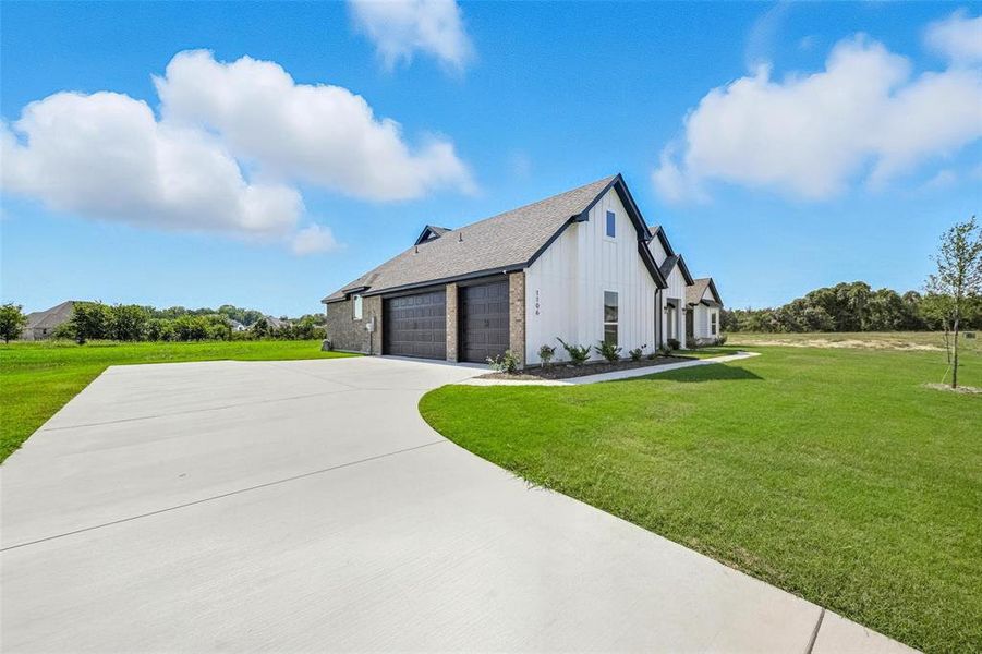 View of home's exterior featuring a yard, board and batten siding, driveway, a shingled roof, and an attached garage View of home's exterior featuring a yard, board and batten siding, driveway, a shingled roof, and an attached garage