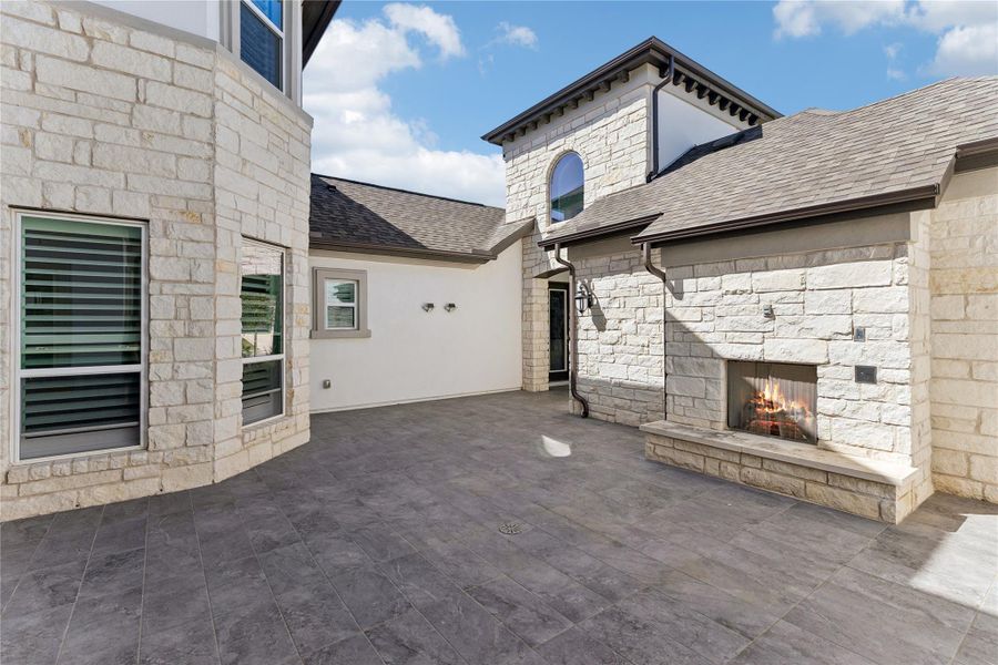 An inviting outdoor living space features a built-in stone fireplace, perfect for evening gatherings.