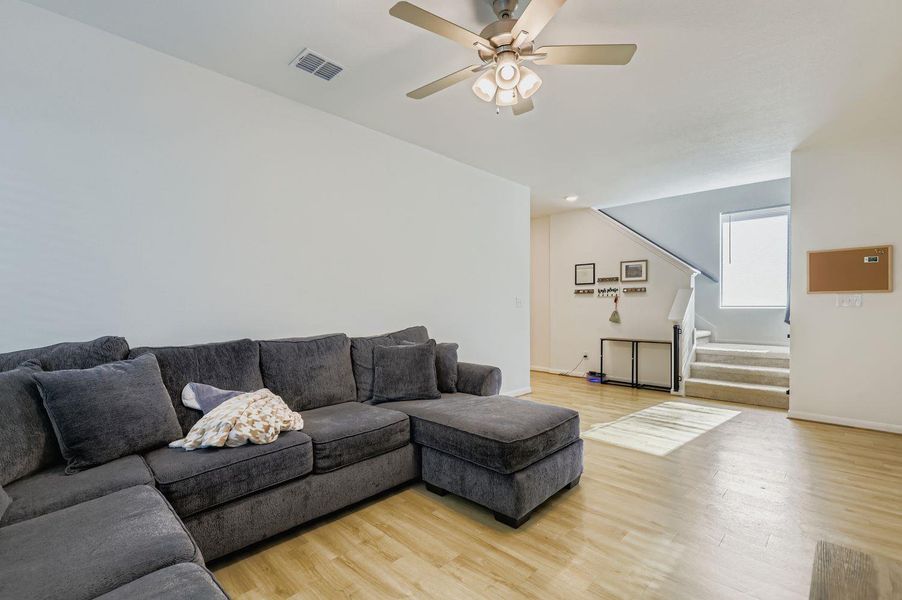Living area featuring stairs, light wood-style flooring, and ceiling fan