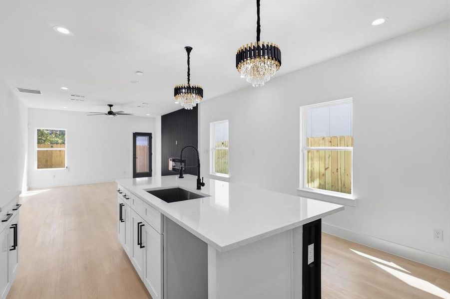 Kitchen island featuring a single-basin sink with a matte black faucet, white cabinetry, and a light-colored countertop Kitchen island featuring a single-basin sink with a matte black faucet, white cabinetry, and a light-colored countertop