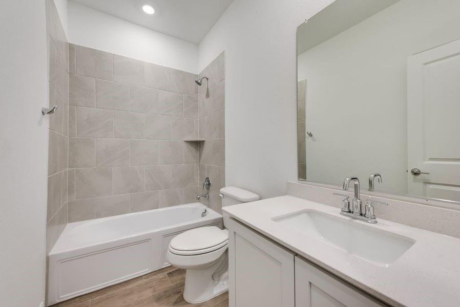 Full bathroom with hardwood / wood-style flooring, vanity, toilet, and tiled shower / bath combo