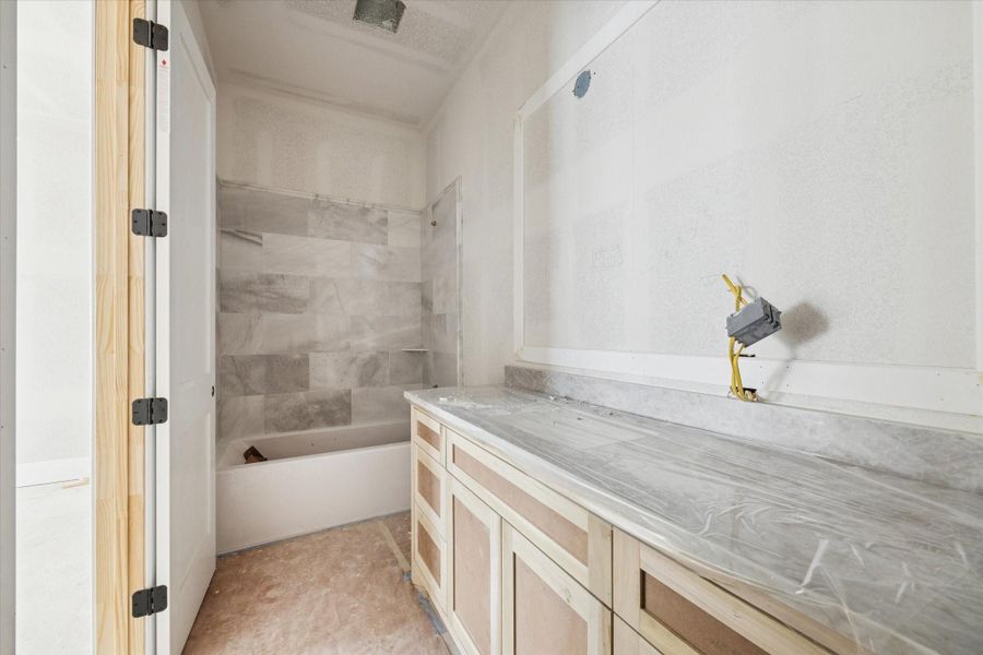 Spacious secondary bathroom with oversized vanity and tile tub surround. Spacious secondary bathroom with oversized vanity and tile tub surround.