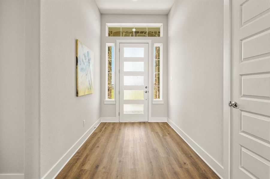 This look back showcases the abundance of natural light that filters into the home through the glass-plated door, sidelights, and transom window above. The space is large enough to house a coat rack and/or bench.