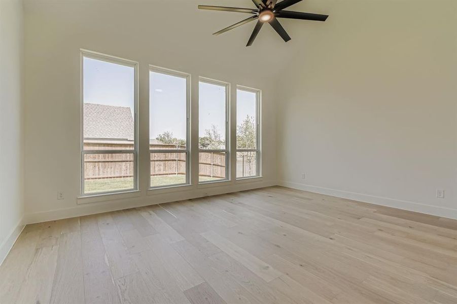 Spare room with light wood-style floors, a ceiling fan, and high vaulted ceiling Spare room with light wood-style floors, a ceiling fan, and high vaulted ceiling