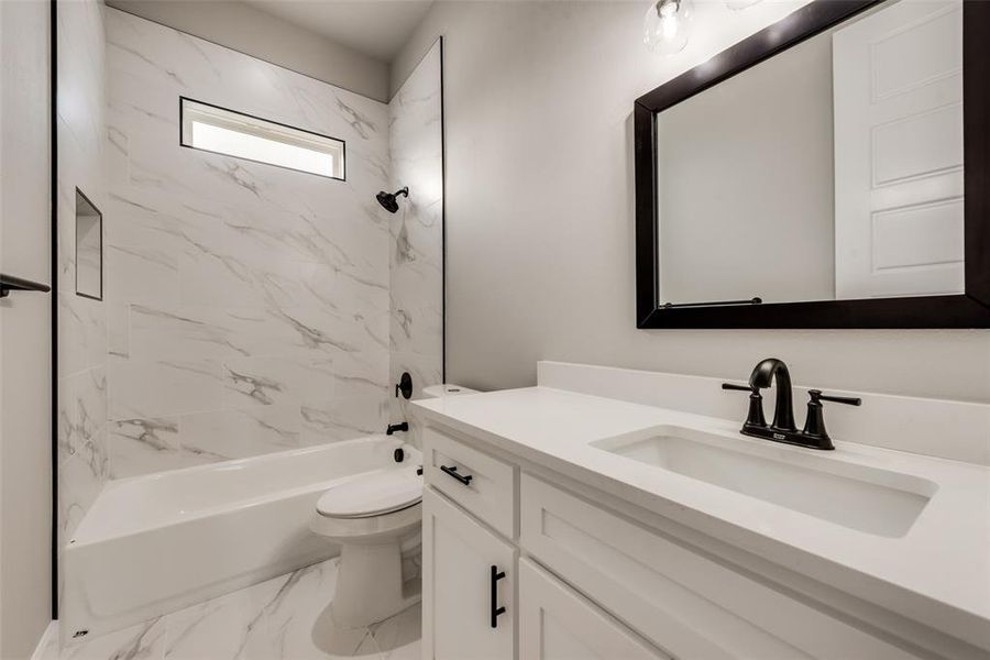 Full bathroom featuring tile patterned flooring, tiled shower / bath, toilet, and vanity