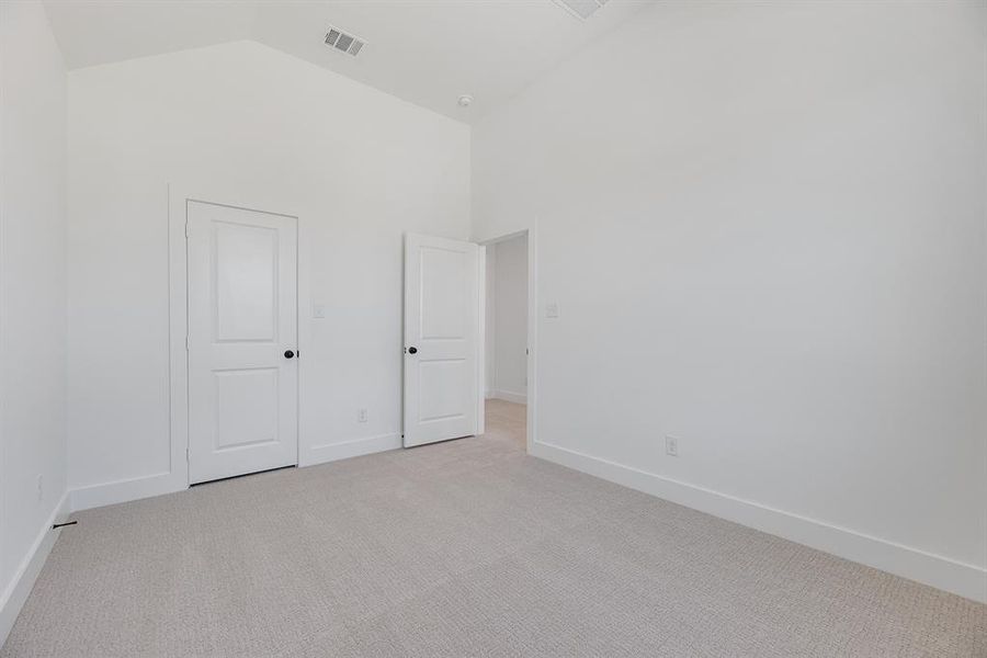 Unfurnished bedroom with light colored carpet and high vaulted ceiling Unfurnished bedroom with light colored carpet and high vaulted ceiling