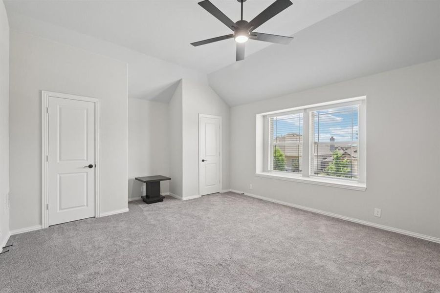Unfurnished bedroom featuring carpet flooring, lofted ceiling, and a ceiling fan Unfurnished bedroom featuring carpet flooring, lofted ceiling, and a ceiling fan