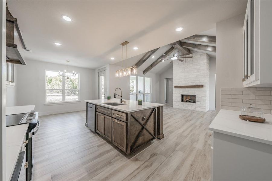 Kitchen with appliances with stainless steel finishes, hanging light fixtures, open floor plan, an island with sink, and dark brown cabinets