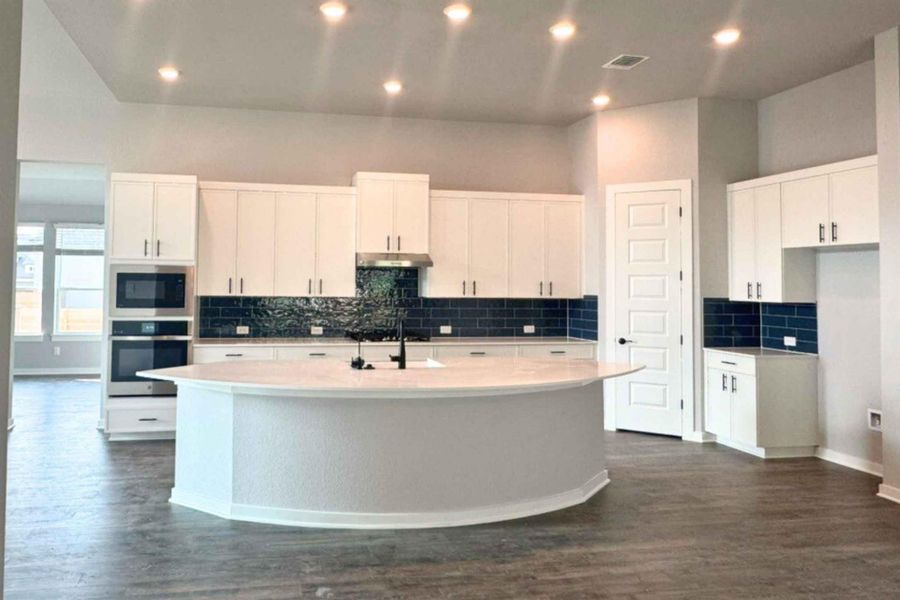 Kitchen featuring stainless steel appliances, white cabinetry, a kitchen island with sink, dark wood-style flooring, and tasteful backsplash Kitchen featuring stainless steel appliances, white cabinetry, a kitchen island with sink, dark wood-style flooring, and tasteful backsplash
