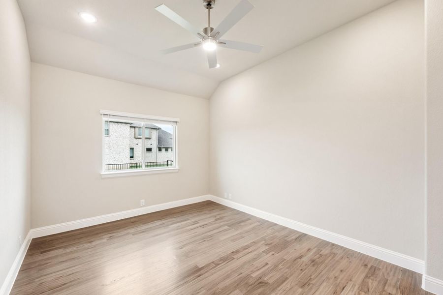 Empty bedroom with vaulted ceiling, ceiling fan, hardwood floors, and single window