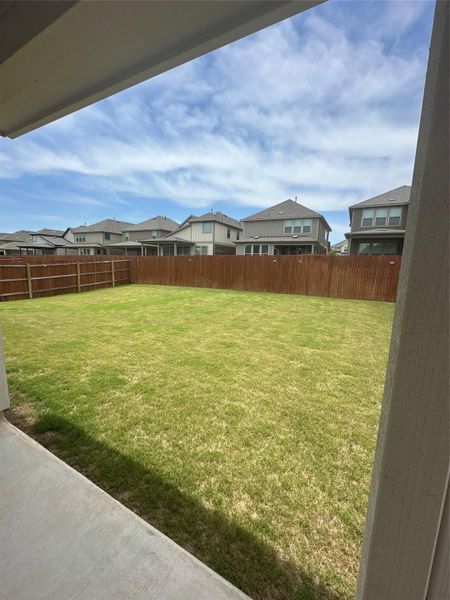 Expansive backyard featuring a manicured lawn, full wood privacy fencing, and a concrete patio space Expansive backyard featuring a manicured lawn, full wood privacy fencing, and a concrete patio space