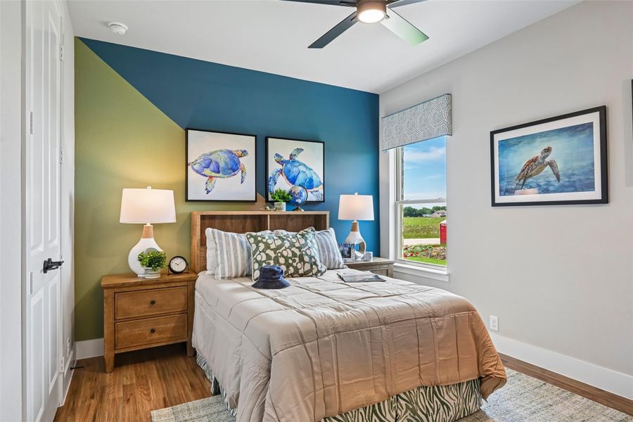 Bedroom with blue and green accent wall, wood bed frame, ceiling fan, and hardwood floors Bedroom with blue and green accent wall, wood bed frame, ceiling fan, and hardwood floors