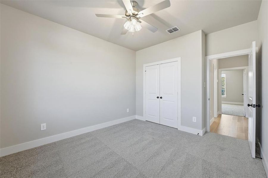 Unfurnished bedroom with carpet, a ceiling fan, and a closet Unfurnished bedroom with carpet, a ceiling fan, and a closet