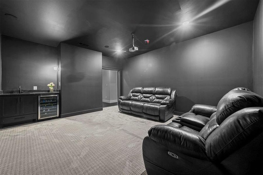 Home theater with wet bar, wine cooler, and carpet flooring