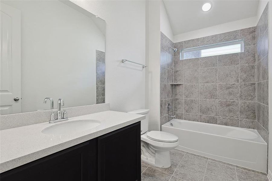 Full bathroom with tiled shower / bath, vanity, lofted ceiling, toilet, and tile patterned flooring