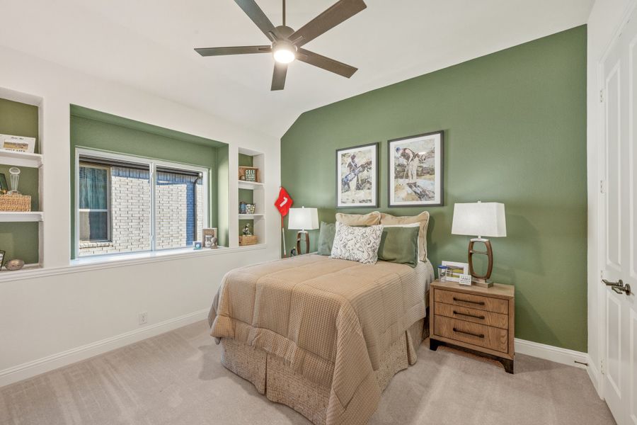 Bedroom with green accent wall, ceiling fan, built-in shelves, and vaulted ceiling