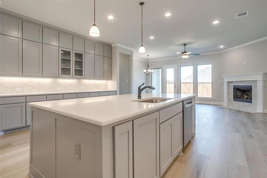 Kitchen with a center island with sink, decorative backsplash, ornamental molding, and a premium fireplace