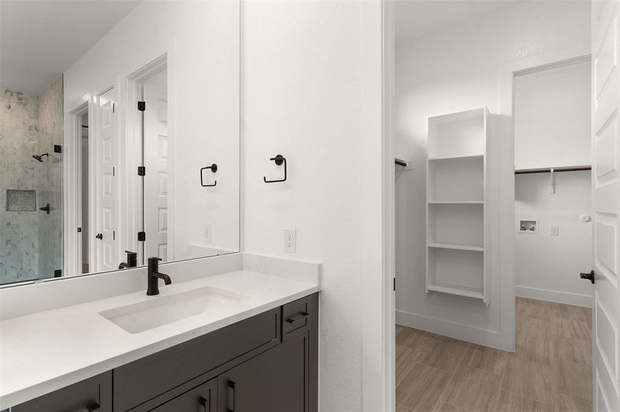 Bathroom with vanity, a spacious closet, and a marble finish shower