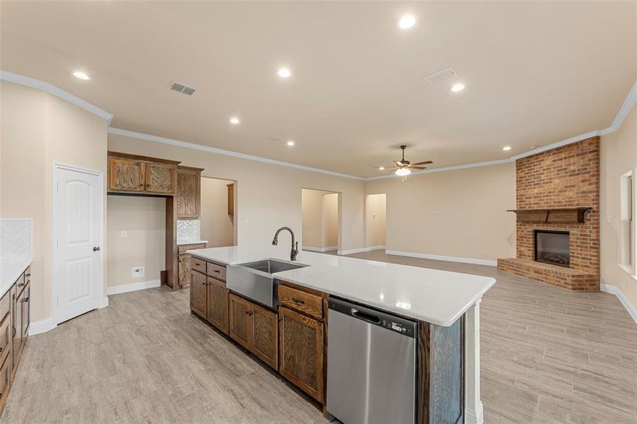 Kitchen with dishwasher, a sink, a ceiling fan, an island with sink, and crown molding
