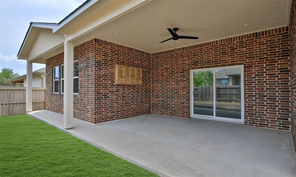 This is a spacious, covered patio with recently installed tile with a ceiling fan, perfect for outdoor relaxation and entertaining. The area is complemented by a well-maintained lawn and offers both privacy and comfort with its brick wall exterior. *New photos coming soon