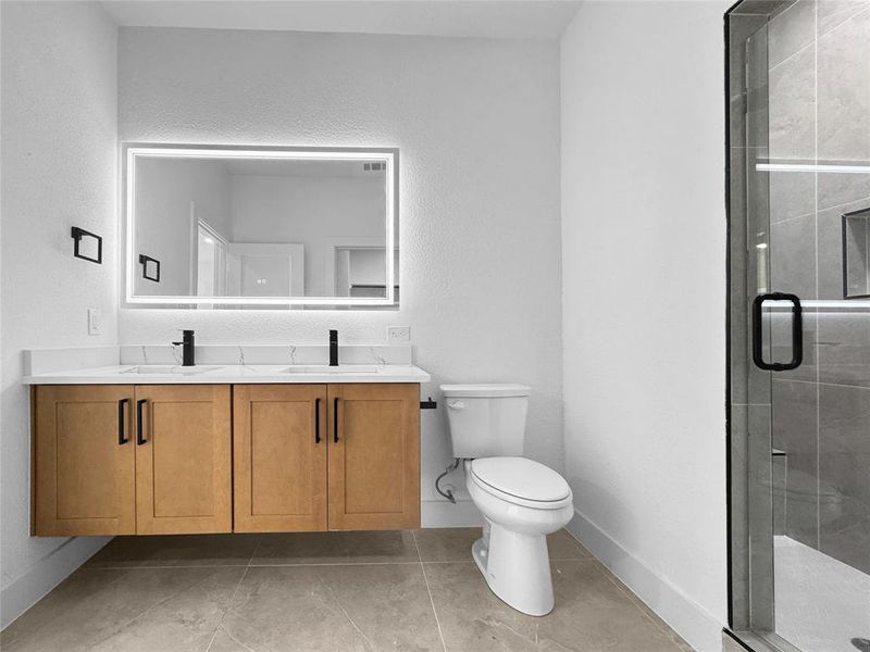 Bathroom featuring double vanity, a shower stall, and light tile patterned floors