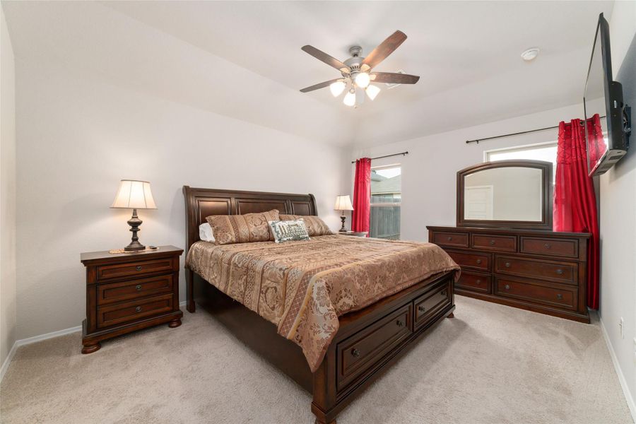 Relaxing primary bedroom with a ceiling fan and soft natural light, creating a peaceful retreat with a bright and airy feel.