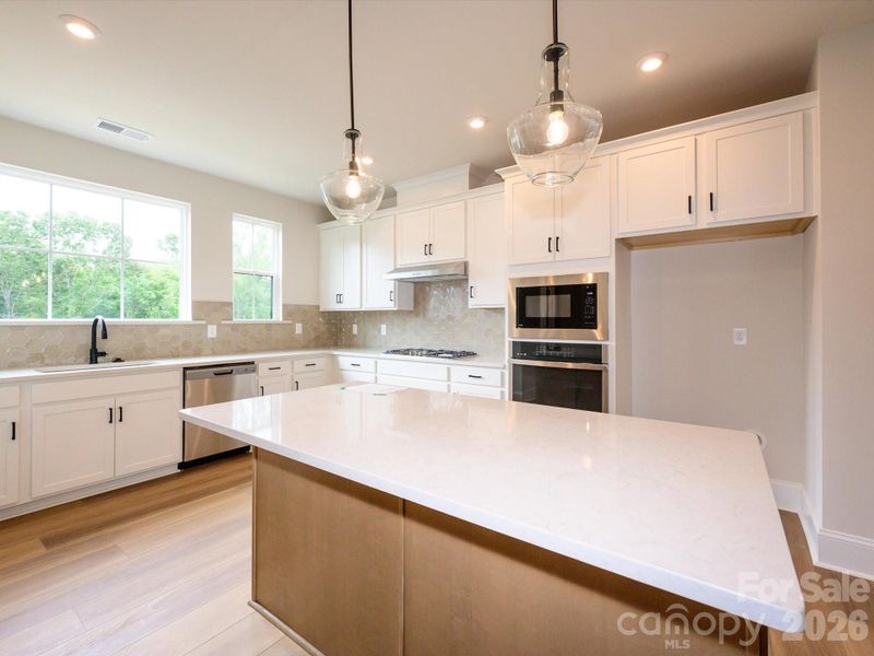 Large Central Island With Quartz Countertops and Pendant Lighting.