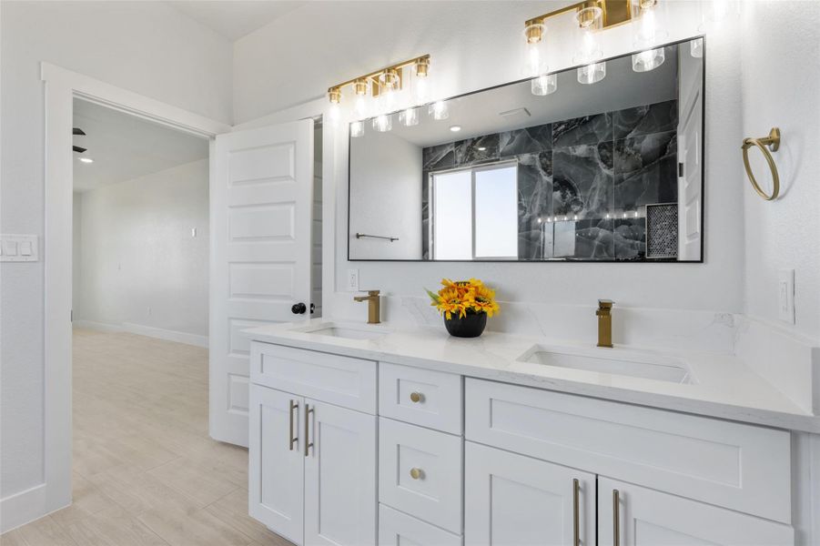 Full bathroom with double vanity, a marble finish shower, and light wood finished floors