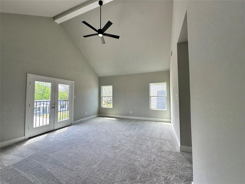 Primary Bedroom upstairs with ceiling fan, beamed ceiling, high vaulted ceiling, light carpet, and french doors