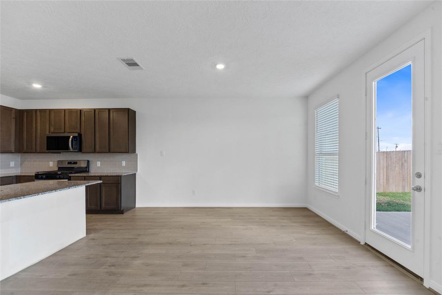 Create lasting memories around the table with family and friends in this inviting dining room! It showcases high ceilings, large windows with privacy blinds, access door to the back patio and yard, vinyl plank flooring, and recessed lighting for a warm and welcoming atmosphere.