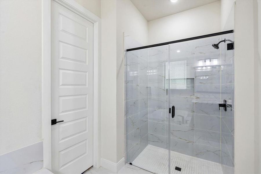 Glass-enclosed shower featuring large format tile surrounds and a hexagonal mosaic floor Glass-enclosed shower featuring large format tile surrounds and a hexagonal mosaic floor