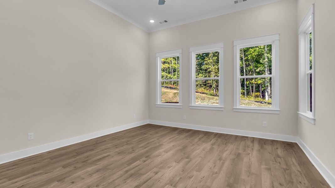 First floor bedroom with windows on multiple sides and hard surface flooring (Representative of completed home)