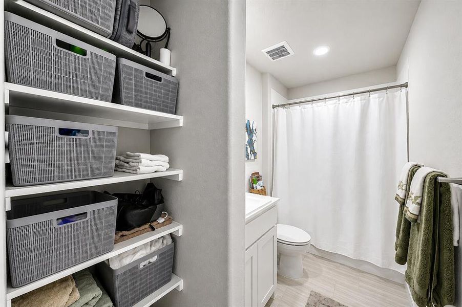 Full bathroom featuring a white vanity with integrated sink, toilet, and shower with curtain rod