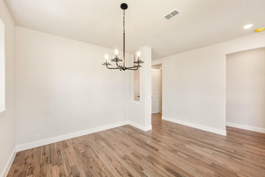 Empty dining room with hardwood floors, white walls, and a black chandelier overhead Empty dining room with hardwood floors, white walls, and a black chandelier overhead
